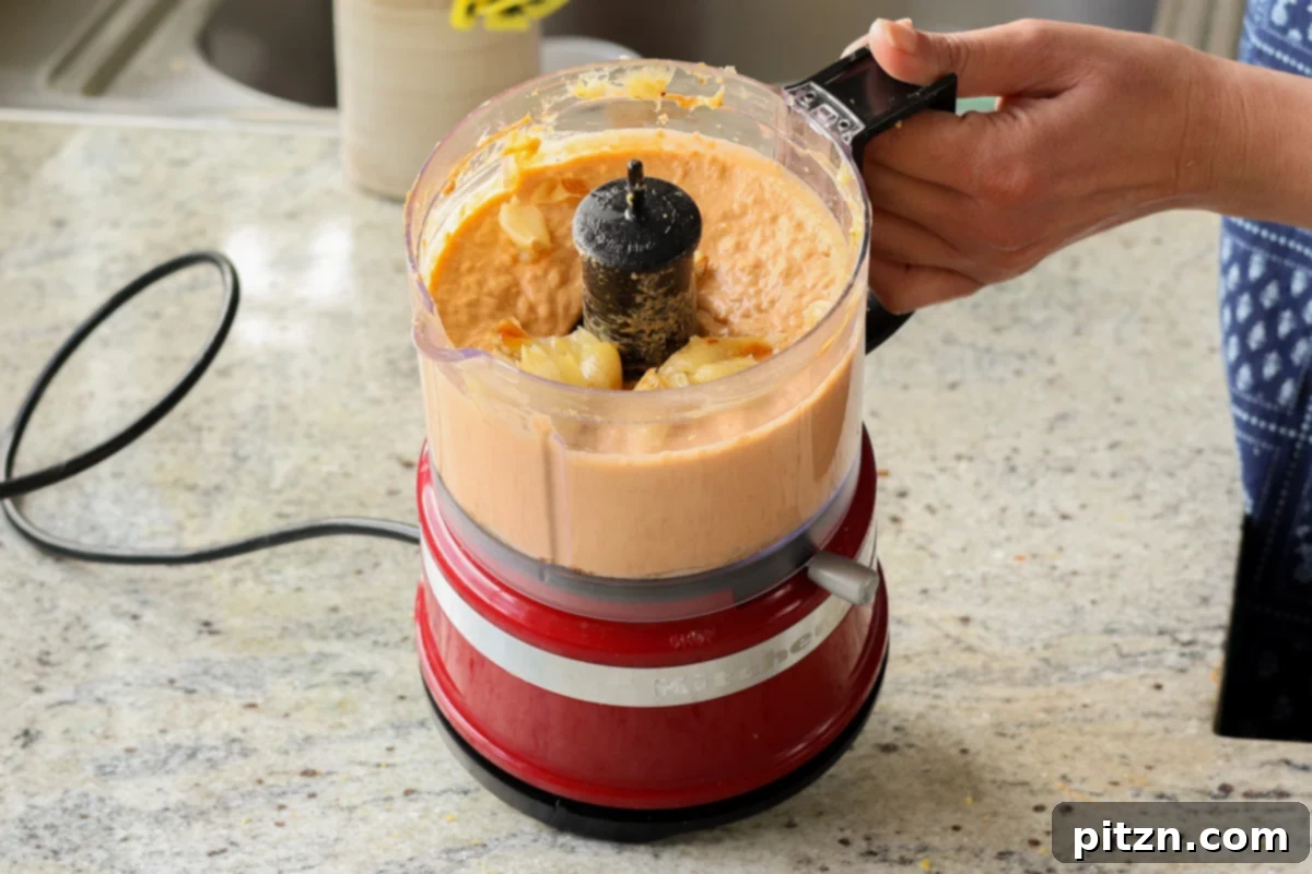 Adding roasted garlic to the bean puree in the food processor