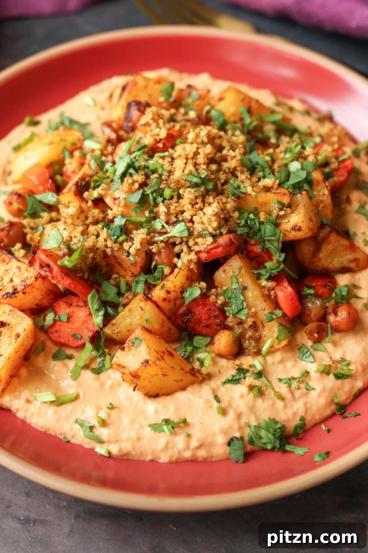 Close-up of harissa bean puree topped with roasted vegetables and baharat walnuts