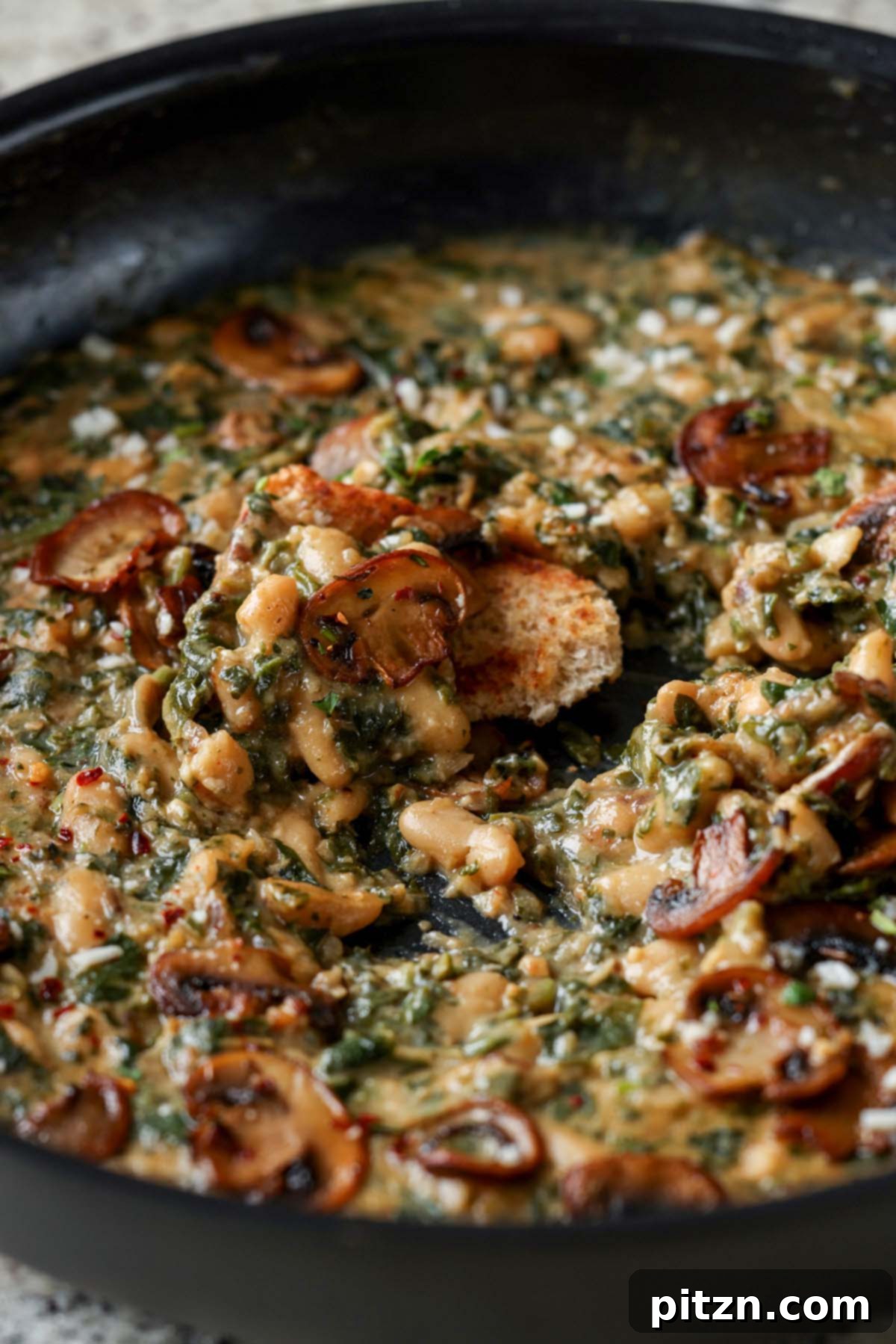 Dipping bread into Spinach Mushroom Beans