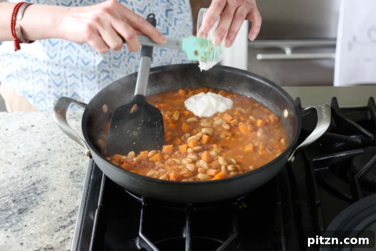 Aromatic Sweet Potato and White Bean Curry Stew 18 adding vegan cream to the pan