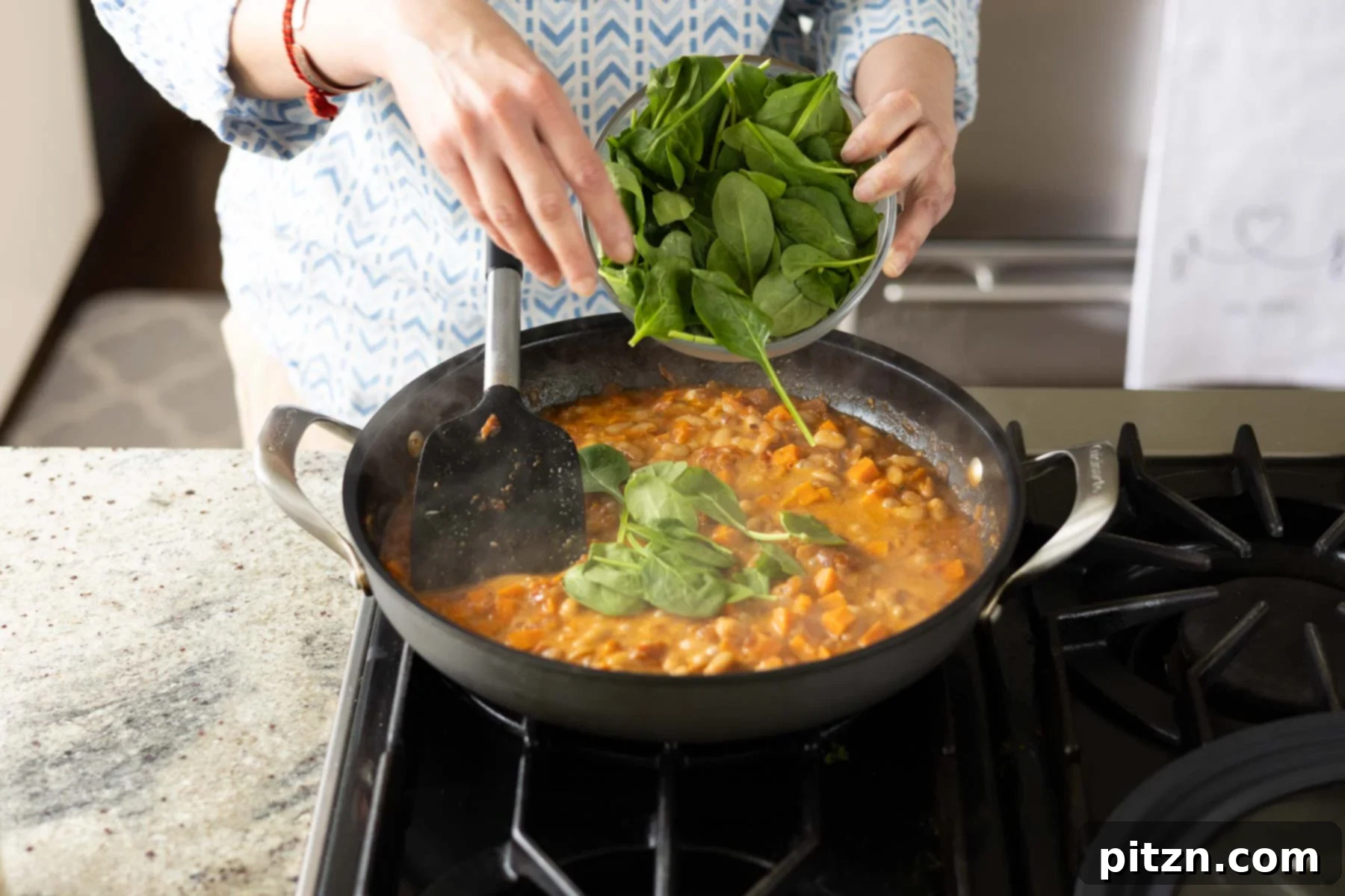 Aromatic Sweet Potato and White Bean Curry Stew 19 adding spinach to the pan