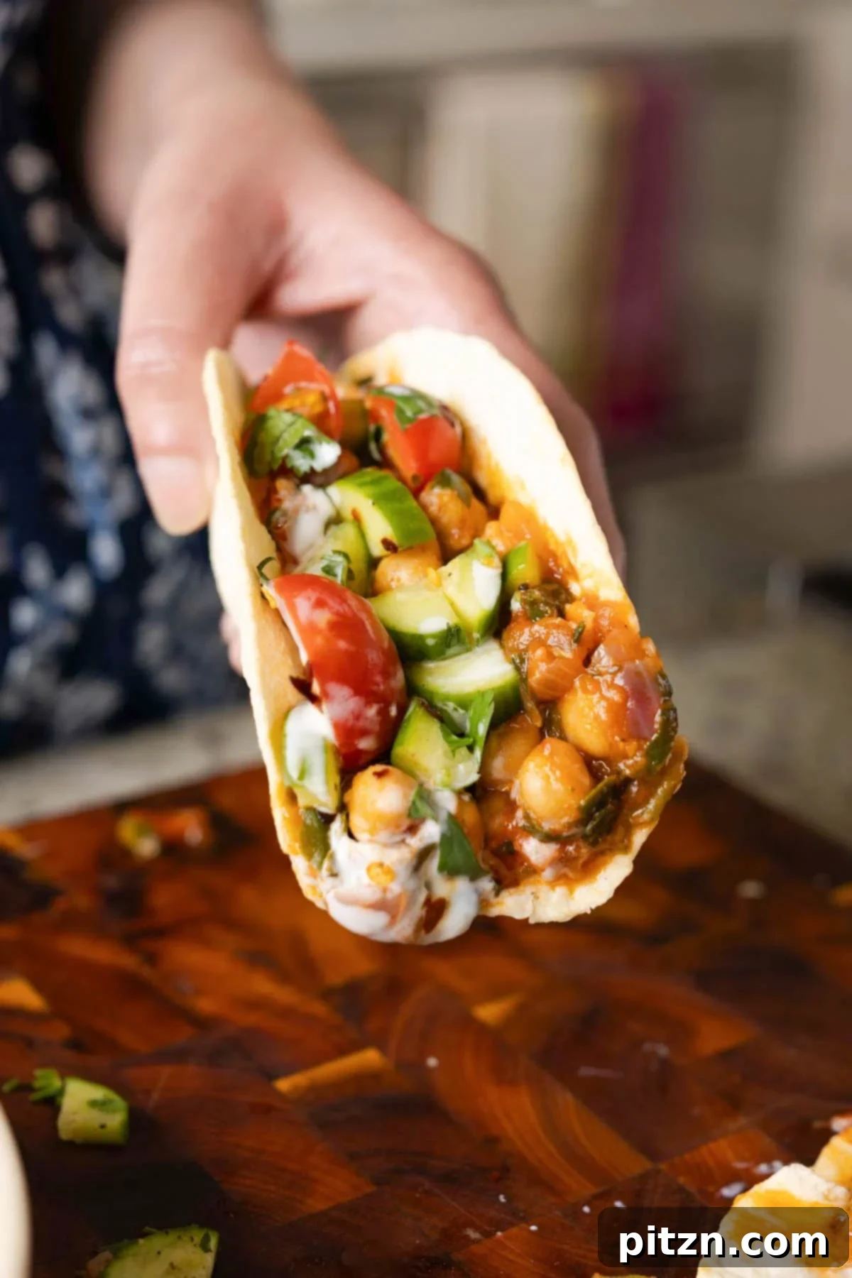 Peri Peri Pan Roasted Chickpeas 5 hand holding a wrap with peri-peri chickpeas topped with the salsa and other garnishes